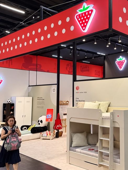 Messestand mit rotem Fries, Leuchtlogo und Kindermöbeln