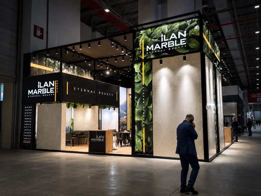 Dunkler Messestand mit beleuchteten Natursteinplatten