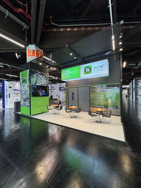 Messestand mit grünen Grafikflächen, Besprechungsbereich und Leuchtschild