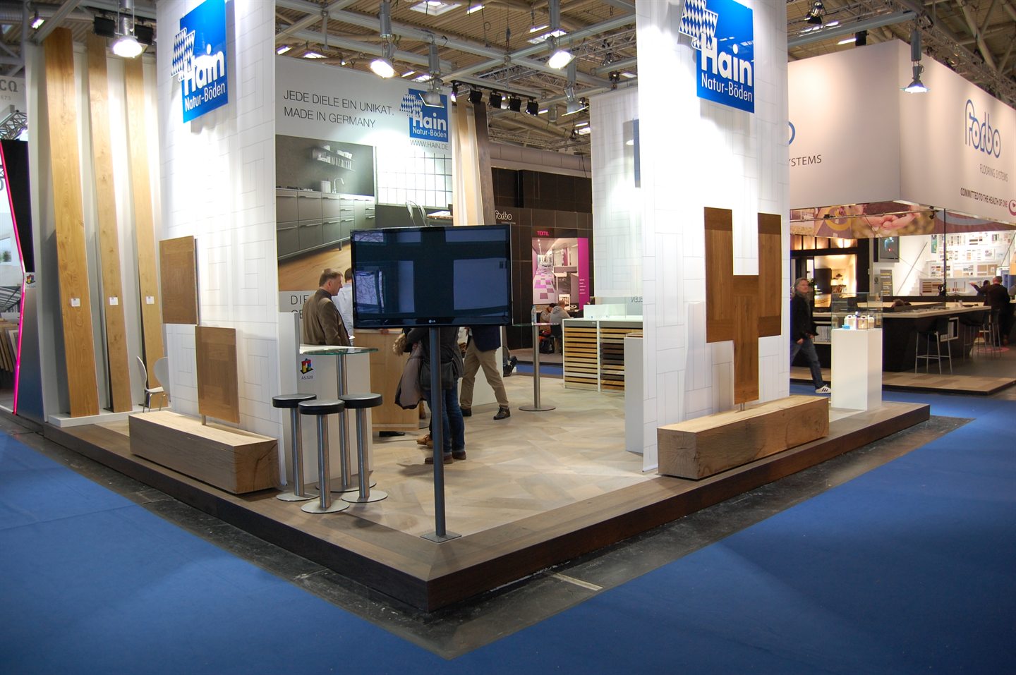 Weißer Messestand mit Holzintarsien und Sitzbänken aus Massivholz