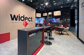 Messestand mit Holzlamellen, roten Sesseln und Bildschirmwand